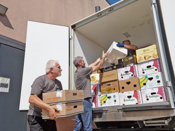 Due volontari caricano il camion per consegnare gli alimenti recuperati